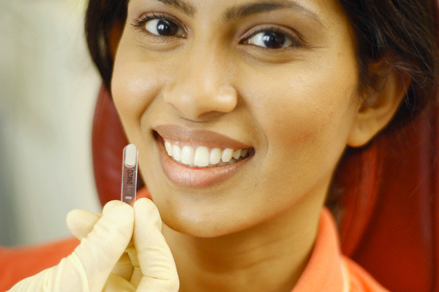 Dentist comparing tooth whitening sample to patient's teeth