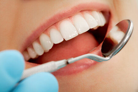 Close-up of patients open mouth during oral checkup with mirror 
